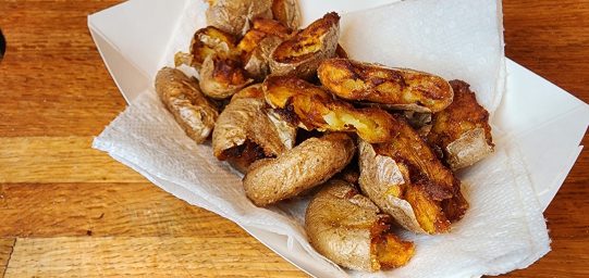 paper container of small potatoes flattened and fried to perfection. giving the most surface area of fried goodness.